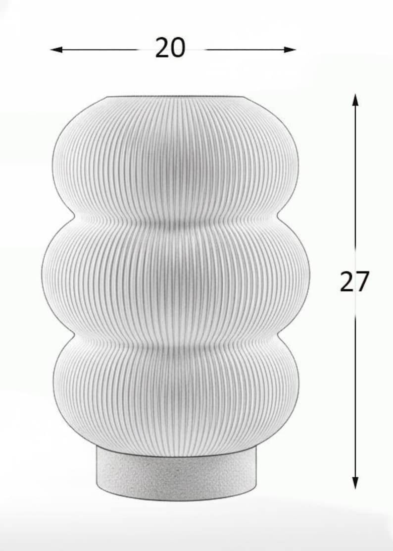 May include: A white vase with a ribbed, three-tiered bulbous body and a solid cylindrical base. The vase features a width of 20 units and a height of 27 units as indicated by the black dimension lines and arrows overlaid on the image.