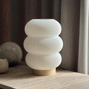 Lampe à poser design en PLA biosourcé blanc mat, style scandinave et organique, posée sur un meuble en bois.
