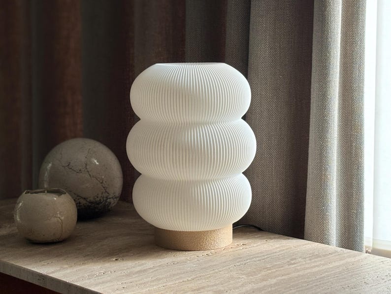 Lampe à poser design en PLA biosourcé blanc mat, style scandinave et organique, posée sur un meuble en bois.