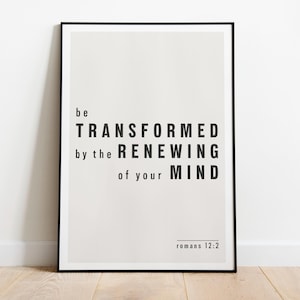 May include: A framed print with a black border, featuring the text "be TRANSFORMED by the RENEWING of your MIND" in bold black font. The text is centered on a light beige background, with "Romans 12:2" at the bottom.