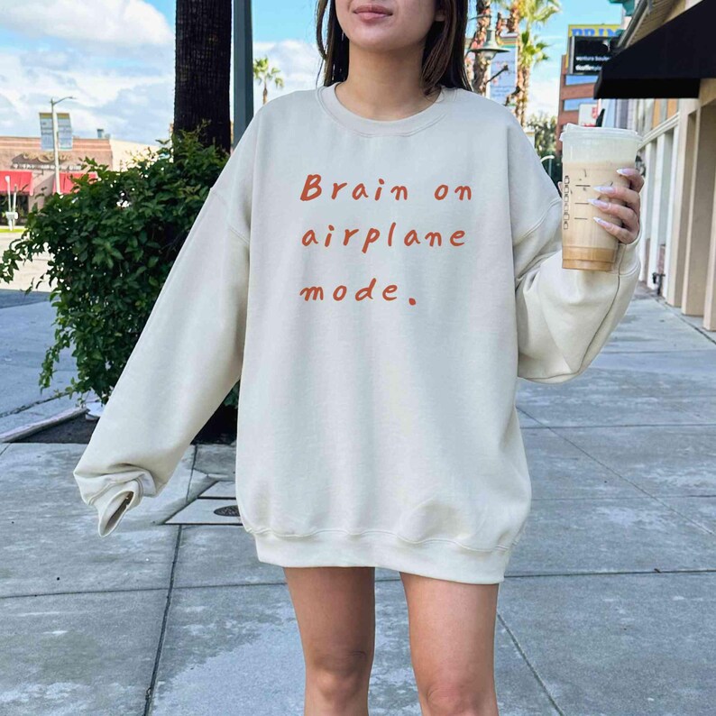 K&ouml;nnte beinhalten: Cremefarbenes Sweatshirt mit dem Schriftzug "Brain on airplane mode." in Rot-Orange. Das lang&auml;rmlige Rundhals-Sweatshirt hat eine lockere Passform.
