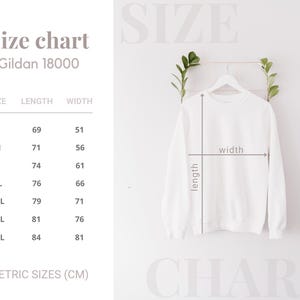 K&ouml;nnte beinhalten: Ein wei&szlig;es Gildan 18000 Sweatshirt auf einem Kleiderb&uuml;gel, mit einer Gr&ouml;&szlig;entabelle, die L&auml;ngen- und Breitenma&szlig;e in Zentimetern zeigt. Die Tabelle enth&auml;lt die Gr&ouml;&szlig;en S bis 4XL. Der Text "Size chart" steht oben.