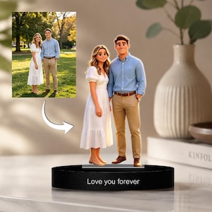Könnte beinhalten: Eine personalisierte Figur eines Paares, gekleidet in einem weißen Kleid und einem blauen Hemd mit beigefarbener Hose, auf einem schwarzen Sockel. Auf dem Sockel steht "Love you forever". Ein eingesetztes Foto zeigt das Paar in einem Park.