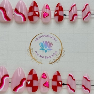 May include: Set of almond-shaped press-on nails with various designs. Some nails feature a pink base with red and white wavy lines. Others have a red and white checkerboard pattern with a white heart. Some nails have a pink heart.