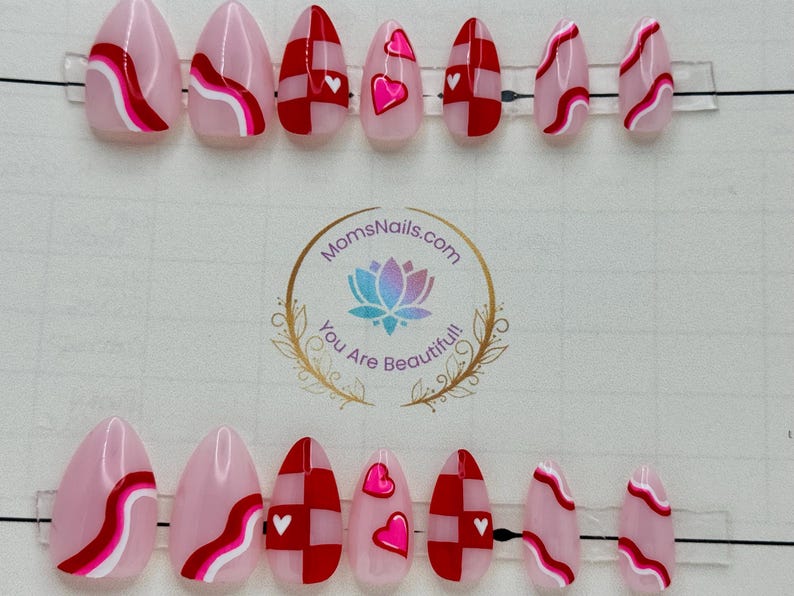 May include: Set of almond-shaped press-on nails with various designs. Some nails feature a pink base with red and white wavy lines. Others have a red and white checkerboard pattern with a white heart. Some nails have a pink heart.