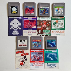 May include: A collection of ten vintage Game Boy cartridges, including Space Invaders, Tetris, Motocross Maniacs, Dr. Mario, Mickey Mouse, F1 Race, Alleyway, and more. The cartridges are arranged in two rows, with the instruction manuals for each game displayed below.