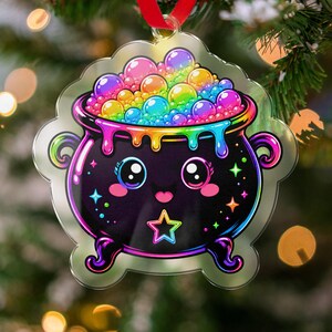 May include: A clear acrylic ornament shaped like a cauldron with a black body, a smiling face, and a star icon. The cauldron is filled with a vibrant, multi-colored rainbow bubble mixture that drips over the rim, accented by small colorful stars.