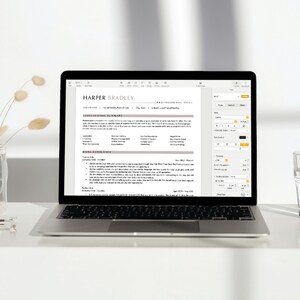 May include: A laptop computer screen displaying a resume template with a light brown background and a dark grey text box. The resume is for Harper Bradley. The screen also shows a menu bar with options for font, colour, and spacing.