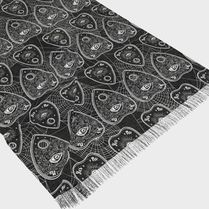 Peut inclure: Jeté de canapé noir et blanc avec un motif répété d'une planchette de Ouija avec les mots "oui", "non", "peut-être" et "au revoir" dessus. La planchette est entourée d'un motif de toile d'araignée.
