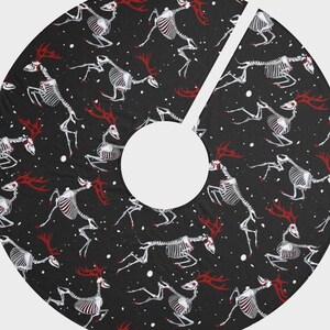 以下が含まれることがあります： 黒地に白のドット模様の背景に、赤色の角を持つ黒と白の骨格の鹿が描かれています。鹿は様々なポーズをとっており、デザイン全体に繰り返されています。これはクリスマスツリーの飾りです。