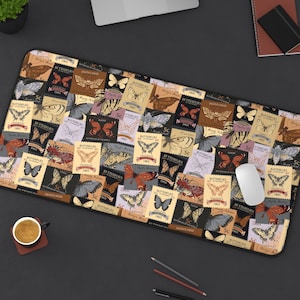 May include: A rectangular desk mat with a collage of vintage butterfly postage stamp designs in various colours. The stamps feature text and illustrations of different butterfly species. A computer mouse rests on the mat.