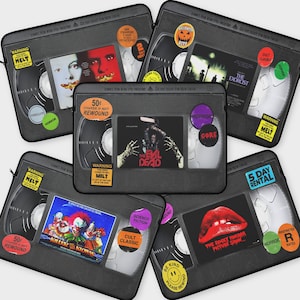 Pode incluir: Uma coleção de oito fitas VHS com capas de filmes de terror. As fitas são pretas com etiquetas e texto coloridos. As etiquetas incluem títulos como "O Exorcista", "O Exorcista" e "Killer Klowns from Outer Space".