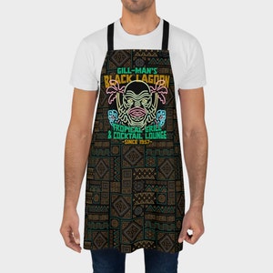 Our Gill Mans Black Lagoon Tropical Grill & Cocktail Lounge Apron is the perfect kitchen cooking accessory gift for any vintage horror movie fan that loves Creature from the Black Lagoon, Universal Monsters, and baking or cooking.