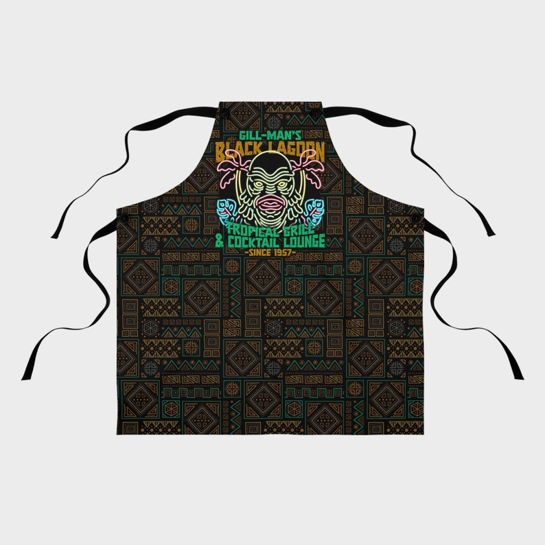 Our Gill Mans Black Lagoon Tropical Grill & Cocktail Lounge Apron is the perfect kitchen cooking accessory gift for any vintage horror movie fan that loves Creature from the Black Lagoon, Universal Monsters, and baking or cooking.