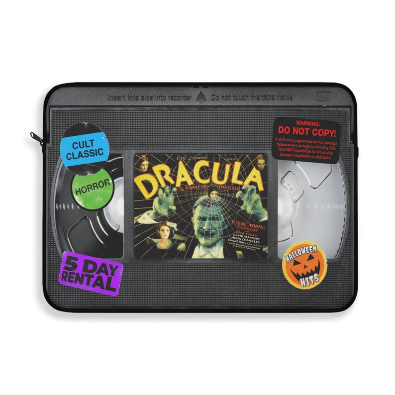 Retro Horror VHS Laptop Sleeve available in three sizes to protect your laptop. Printed on one side with a black backside, edging and zip, the perfect addition to your movie monsters, 80s, 90s, VHS tape Frankenstein, Dracula, themed desk or computer.