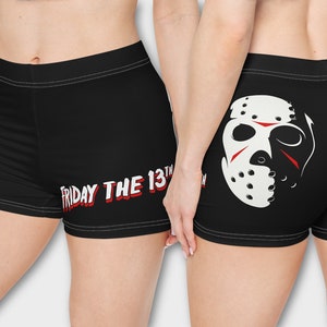Può includere: Shorts sportivi neri con una grafica di una maschera da hockey bianca sul retro e il testo "FRIDAY THE 13TH" sul davanti.