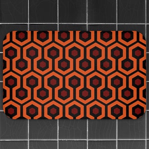 May include: Orange and red bath mat with a geometric pattern. The pattern is made up of repeating hexagons and squares.