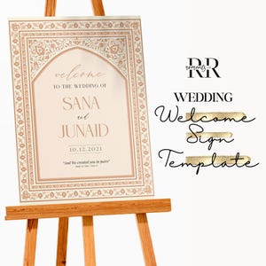May include: A wedding welcome sign on a wooden easel. The sign has a decorative border and features the names SANA and JUNAID, along with the wedding date. The sign also includes the text "welcome" and "And We created you in pairs."