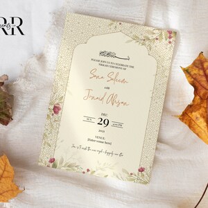 May include: A cream-colored wedding invitation with a floral design and intricate patterns. The invitation announces the Nikkah ceremony of Sana Saleem and Junaid Alisan on December 29th, 2022 at 6:00 PM. The venue is not specified.