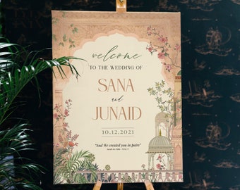 May include: A wedding announcement sign with a floral design and the text "welcome to the wedding of Sana and Junaid 10.12.2021 "And We created you in pairs"