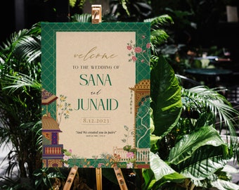 May include: A green and gold wedding welcome sign with intricate floral designs and the text "welcome to the wedding of Sana and Junaid 8.12.2023 "And We created you in pairs"