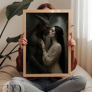 May include: A rectangular wooden frame containing a digital print of a dark-skinned horned creature with glowing eyes facing a pale-skinned person with long black hair wearing a cream-colored long-sleeved dress. The print features the text DREAM DIGITAL BY LISA.