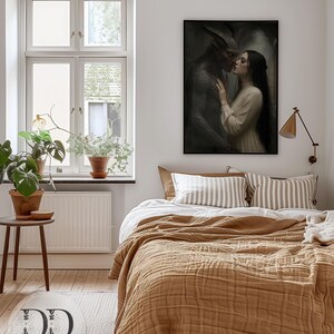 May include: A framed wall art print depicting a dark-skinned horned figure with textured skin standing close to a person with long dark hair wearing a cream-colored long-sleeved garment. The artwork features a moody, atmospheric aesthetic with deep shadows.