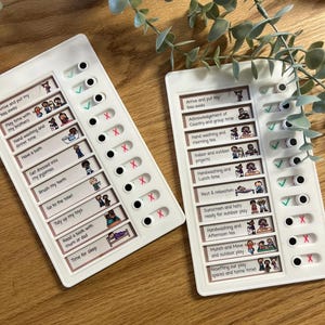 May include: Two white boards with black and red circles. Each board has a list of activities with corresponding illustrations. The activities are for a preschool or daycare setting. The circles are used to mark off completed activities.
