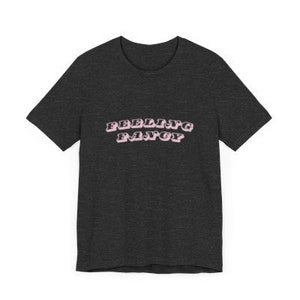 Peut inclure: Un t-shirt gris foncé chiné avec le texte "Feeling Fancy" en lettres roses.
