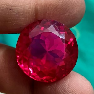 Op de afbeelding: Een dieprode edelsteen met een facetgeslepen vorm. De edelsteen is rond en heeft een hoge glans.