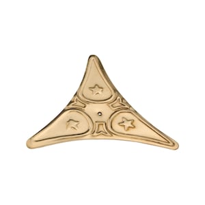 May include: A gold-coloured, triangular decorative corner piece with a star design. The piece has a central hole and three star-shaped embellishments, with a decorative border. Likely for furniture or craft projects.