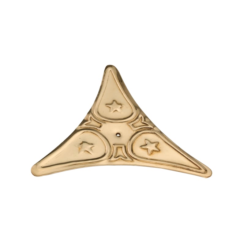 May include: A gold-coloured, triangular decorative corner piece with a star design. The piece has a central hole and three star-shaped embellishments, with a decorative border. Likely for furniture or craft projects.
