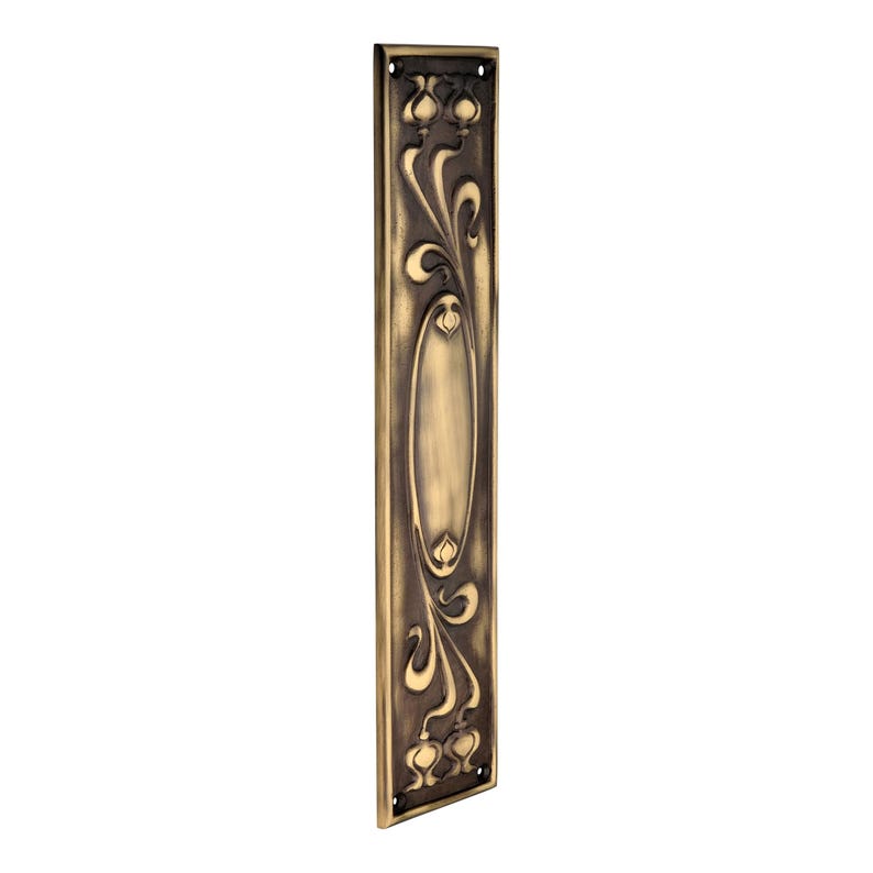 May include: A bronze-coloured door plate with an Art Nouveau design. The rectangular plate features an oval centre and floral and vine motifs. The plate has a dark, aged finish and is likely made of metal. Includes small holes for mounting.