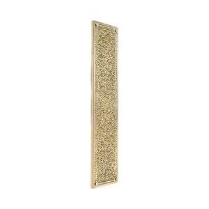 May include: A rectangular, brass-colored door finger plate with an ornate, textured floral pattern. The plate has a slightly aged appearance and is designed for door protection. The edges are framed with a simple border and small screw holes.