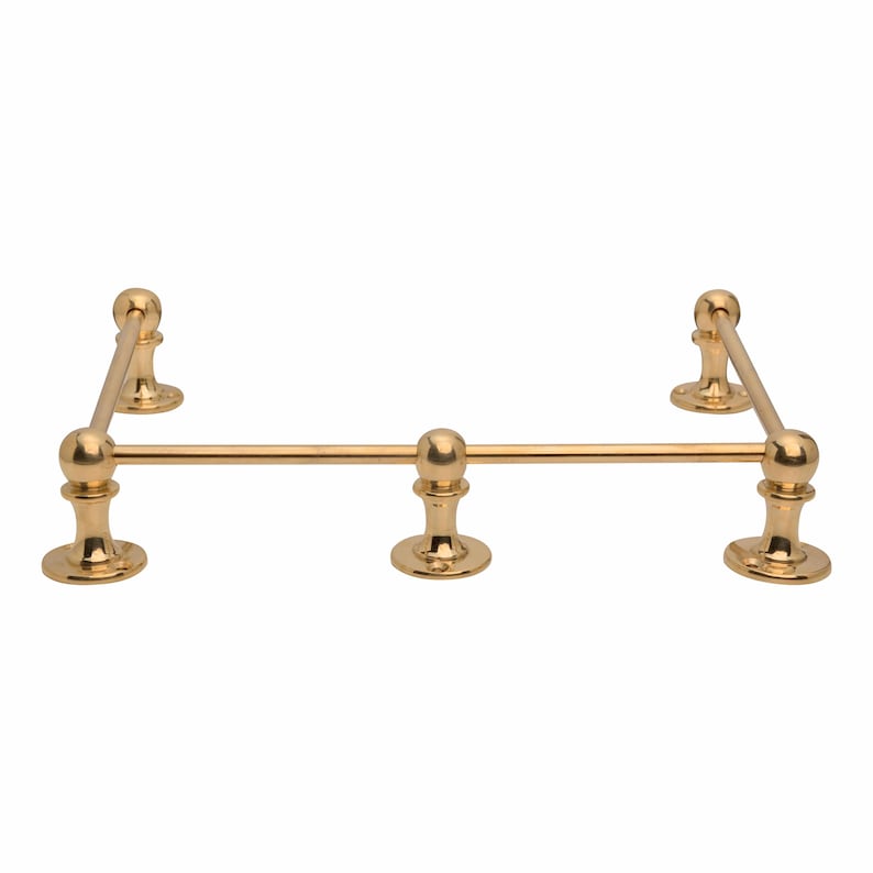 May include: A gold-colored, decorative towel rack with a geometric design. The rack features a series of straight bars connected by rounded, ball-shaped accents. The rack is designed to be mounted on a wall.