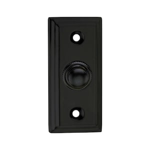 May include: A rectangular, black doorbell button with a rounded center button and two screw holes. The button has a raised, beveled edge and a matte finish. The design is simple and classic.
