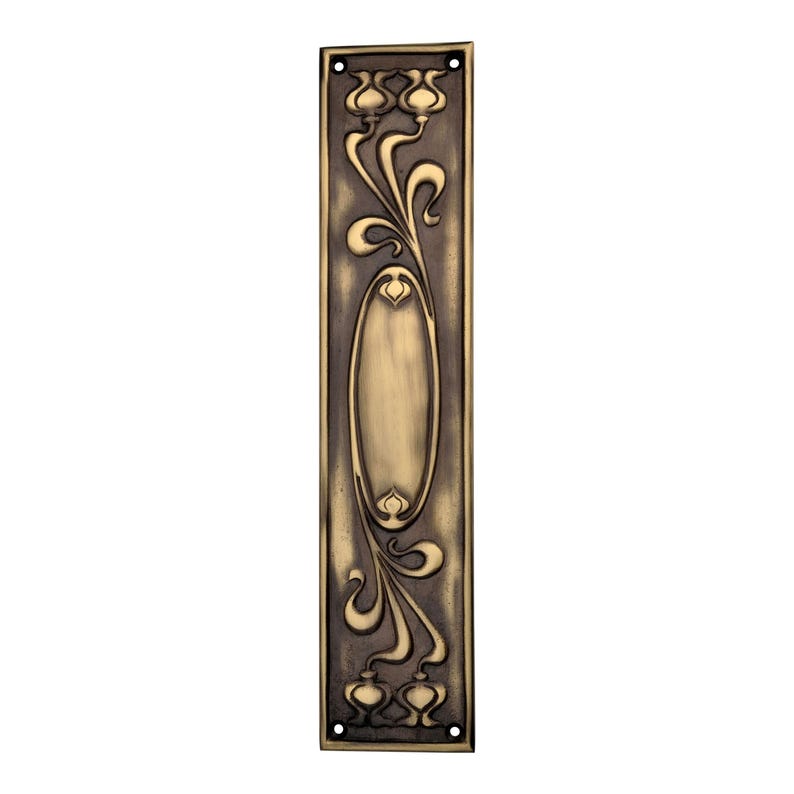 May include: An antique brass door plate with an Art Nouveau floral design. The rectangular plate features an oval centre and decorative floral and swirling patterns. It has four screw holes and a dark, aged finish.