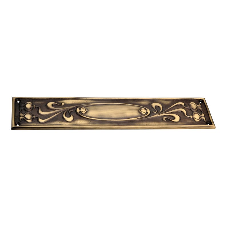 May include: An antique brass-coloured metal plate with an Art Nouveau design. The rectangular plate features an oval centre and stylized floral and swirling patterns. It has four screw holes at each end.