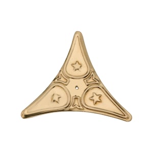 May include: A gold-coloured, triangular decorative furniture corner bracket. The bracket features a star design within each of the three rounded sections. A small hole is centred in the design. The bracket is made of metal.