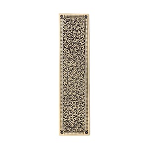 May include: A rectangular, brass-colored door pull with an intricate, repeating floral pattern. The edges are lined with small, evenly spaced dots. The design is centered on a dark background, creating a contrast. The door pull has a vintage aesthetic.