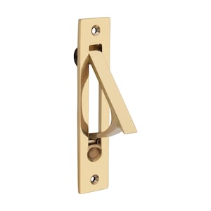 Peut inclure: Une poignée encastrée rectangulaire de couleur dorée avec une poignée incurvée. La poignée est inclinée et s'étend d'une forme ovale encastrée. La poignée a deux trous de vis et un petit bouton noir.