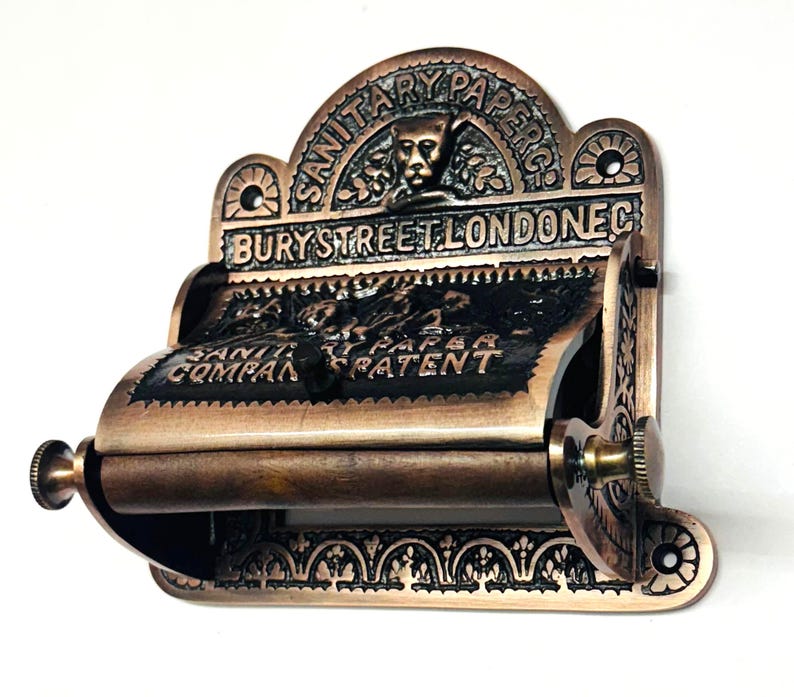 May include: Antique brass toilet paper holder with intricate detailing. The holder features the text "SANITARY PAPER CO. BURY STREET LONDON EC."