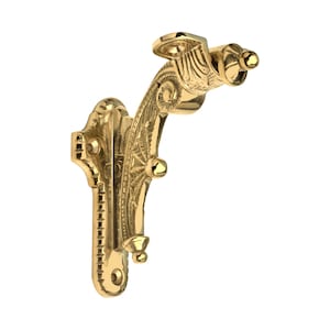 Puede incluir: Soporte de pared dorado y ornamentado con intrincados detalles y acentos decorativos. El soporte presenta un brazo curvo y múltiples puntos de montaje, ideal para sostener estantes o elementos decorativos. El diseño incluye pequeños remates redondeados.