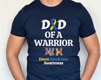 May include: A navy blue t-shirt with the text "D&D of a Warrior" and a yellow and blue ribbon. Below the text are three colourful socks hanging on a clothesline. The text "Down Syndrome Awareness" is below the socks.