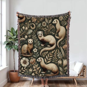 May include: A woven throw blanket with a dark green background featuring a repeating pattern of ferrets and floral designs. The ferrets are depicted in shades of brown and white, and the flowers are in shades of pink, white, and green.