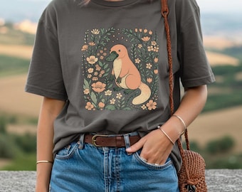 May include: Dark grey t-shirt featuring a cartoon platypus surrounded by flowers. The platypus is peach-colored with a green beak and is set against a floral background with peach and cream-colored flowers.