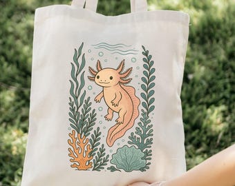 May include: A cream tote bag with a cartoon axolotl design. The axolotl is peach-coloured with pink gills and a long tail, swimming amongst green seaweed and orange coral. The bag has two cream-coloured handles. The design is printed on a natural-coloured fabric.
