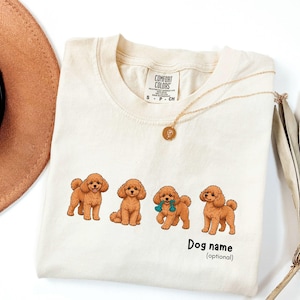 Peut inclure: Un t-shirt à manches courtes de couleur crème avec un motif représentant quatre caniches bruns dans diverses positions. Le t-shirt porte l'inscription "Dog name (optional)" en noir sous les chiens et une étiquette Comfort Colors au col.
