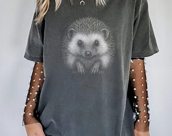 May include: Dark grey t-shirt featuring a detailed illustration of a hedgehog. The graphic is in black and white, with the word "Pepper" in a white circle at the bottom right. The shirt has short sleeves.
