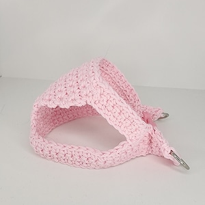 May include: Pink crocheted dog harness with two silver metal D-rings.